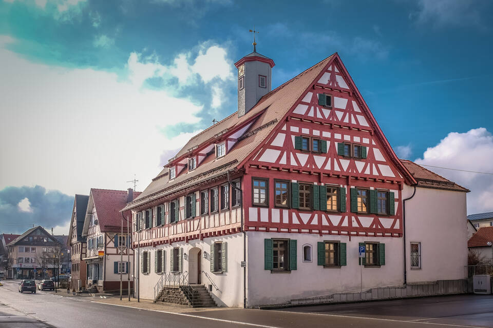 EIn älteres Fachwerkhaus liegt an einer innenstädtischen Straße vor blauem Himmel
