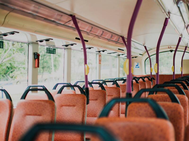 Der Innenraum eines leeren Busses mit orangefarbenen Sitzen und lila Haltestangen wird gezeigt.