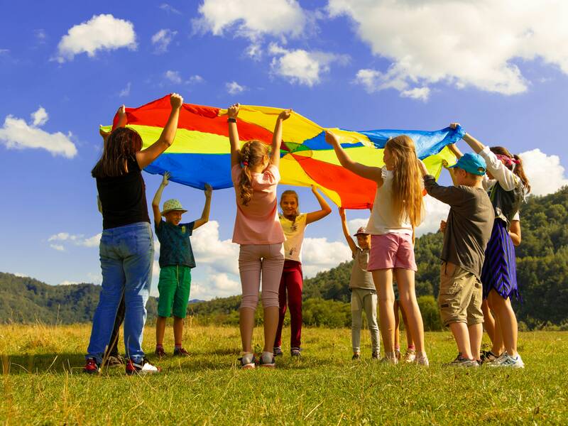 Kinder spielen mit einem großen bunten Tuch