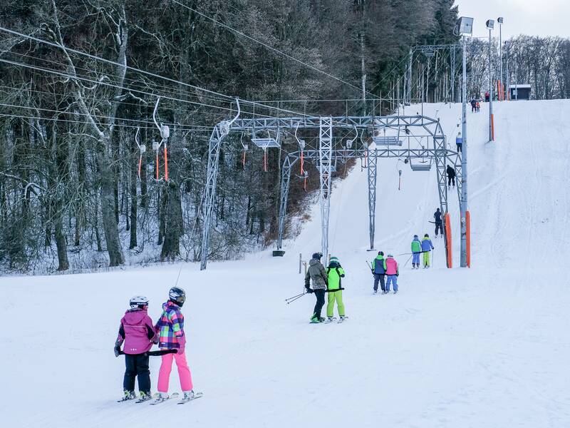 Mehrere Skifahrer nutzen den Schlepplift in Laichingen auf einer schneebedeckten Piste, umgeben von Bäumen.