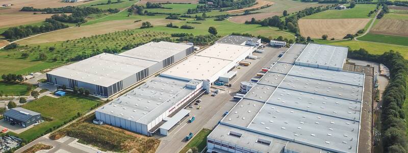 Luftbild 2 großer Hallen im Laichinger Industriegebiet mit Landschaft im HIntergrund